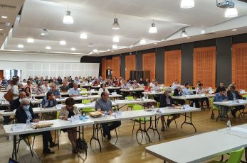salle de conférence avec des tables, toutes ou presques, sont remplies par des gens