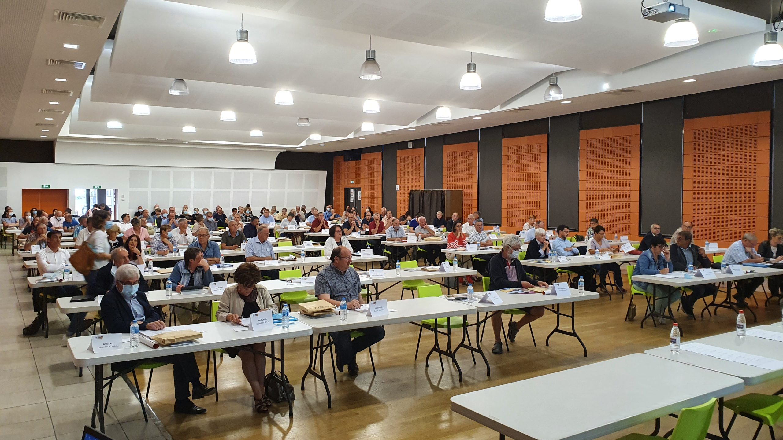 salle de conférence avec des tables, toutes ou presques, sont remplies par des gens