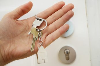 Dans uen main il y a un Jeu de clé avec un porte clé en forme de maison