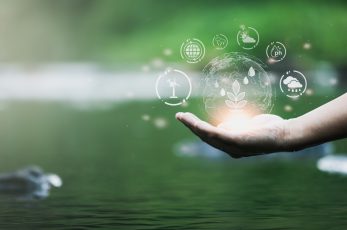 Au-dessous de l'eau d'une rivière, une main tendue vers le ciel t sur laquelle se trouve des bulles de lumière