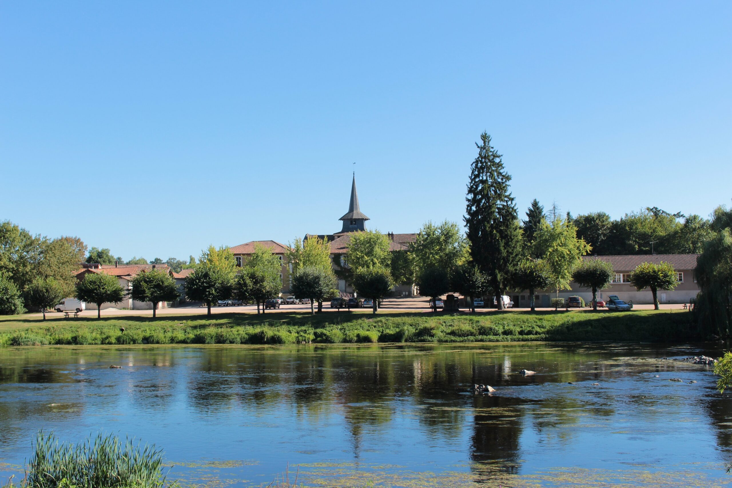 Photo d'Exideuil-sur-vienne depuis la rive, l'église est en fond avec un grand ciel bleu
