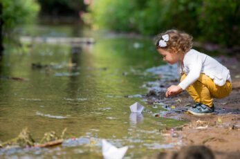 Petite fille sur le bord d'un cours d'eau qui regarde l'eau