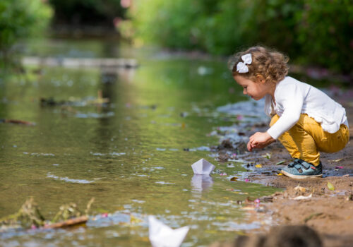 Petite fille sur le bord d'un cours d'eau qui regarde l'eau
